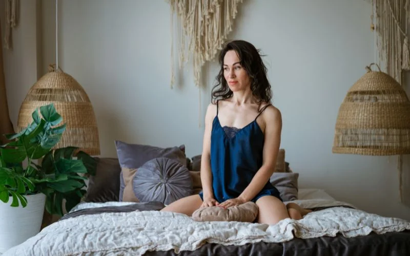 woman sitting on bed in blue lingerie