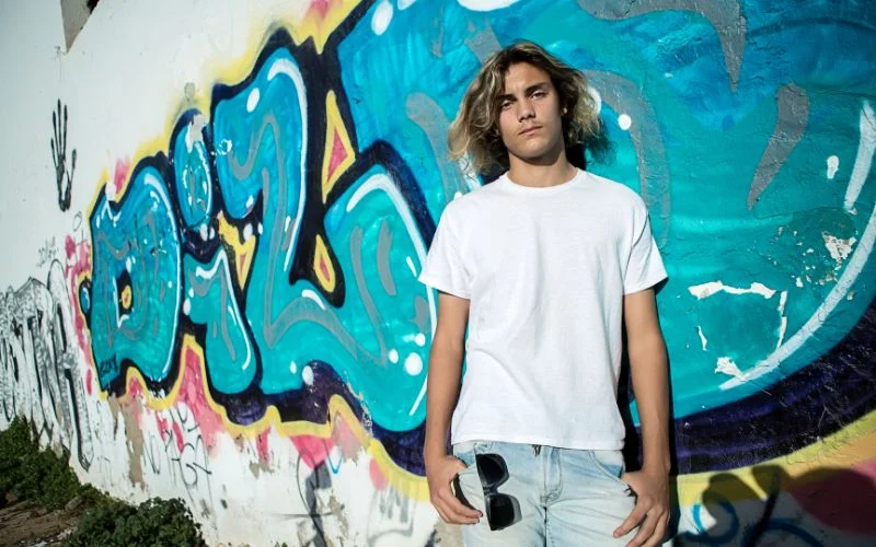boy standing against a graffiti wall