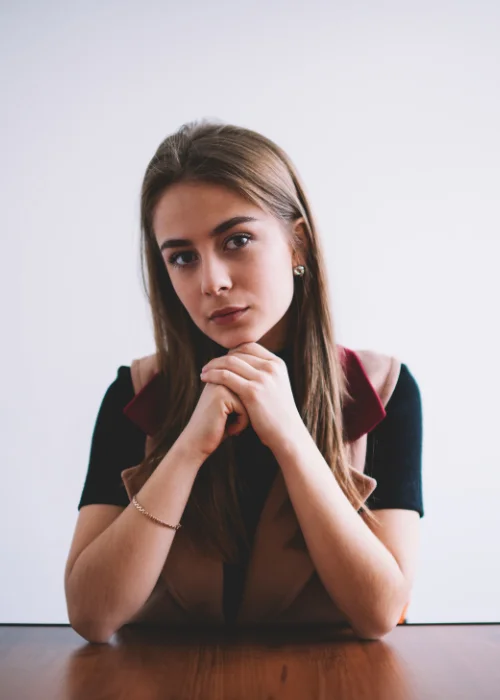 Sitting on the table with chin resting on hands headshot pose