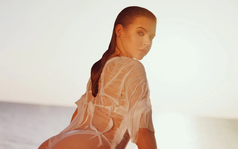 nude beach poses - model in wet clothes looking over the shoulder - nude beach photoshoot, nude beach portraits, best nude beach pictures, beach nude photos