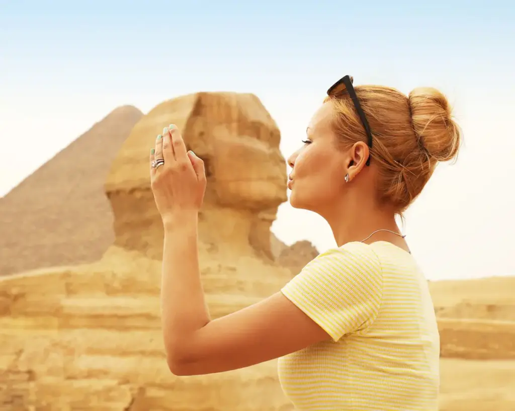 A woman posing while kissing the Sphinx