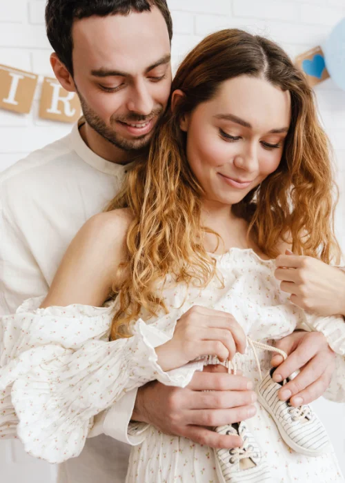a couple posing with baby mittens