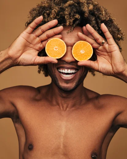 man holding orange as eyes