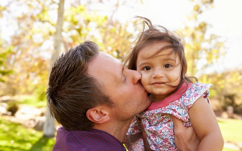 dad kissing his baby daughter while she smiles