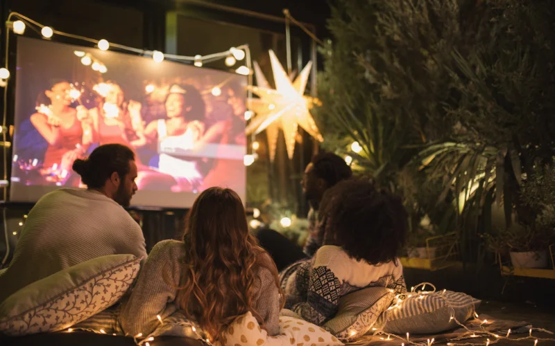 friends watching a movie on projector outdoors