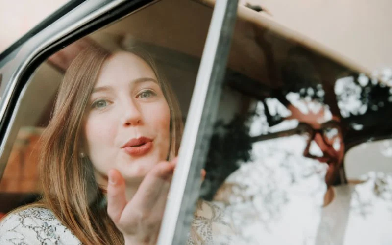 a model blowing a kiss while sitting in a car