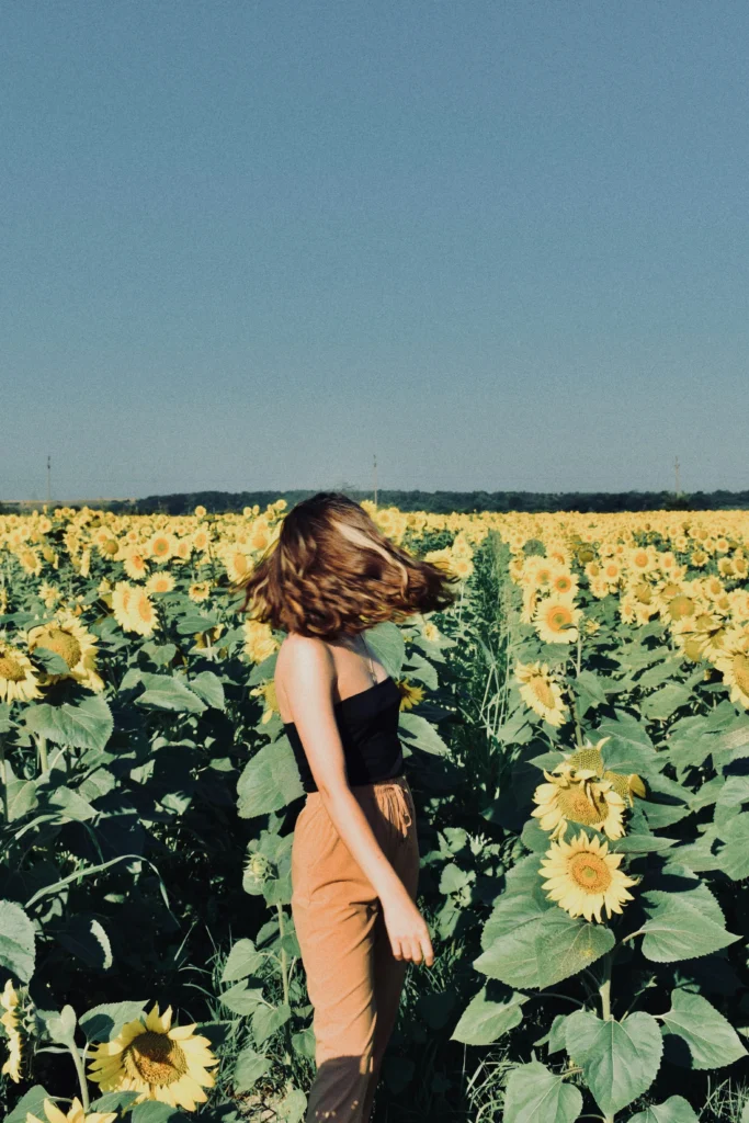 an aesthetic photo of a girl posing in a sunflower field