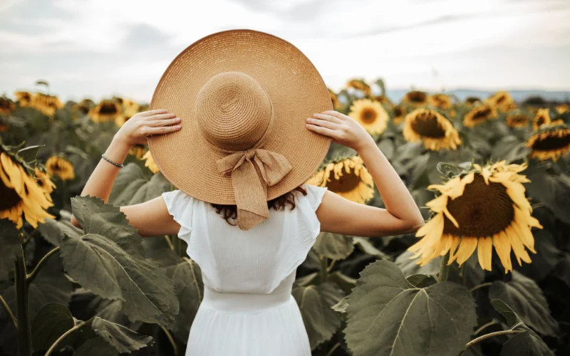 a model posing with a hat in a sunflower field