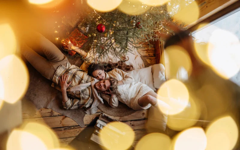 A couple posing on the floor next to the Christmas tree captured from above