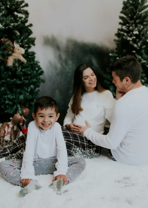 a kid posing with parents at the Christmas themed maternity shoot