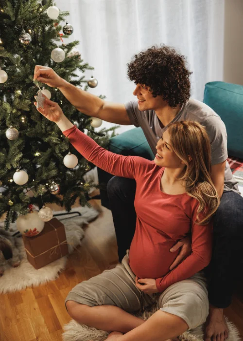 Christmas maternity photo ideas - couple posing while decorating