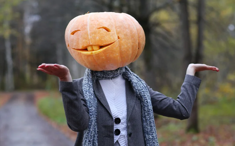a woman wearing a silly looking pumpkin head for a photoshoot