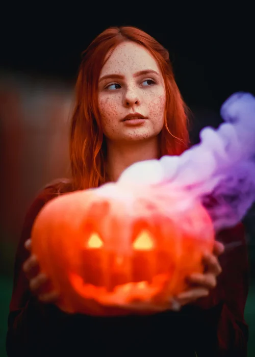 A woman posing with a Pumpkin head with smoke coming out of it - Jack O Lantern head photoshoot