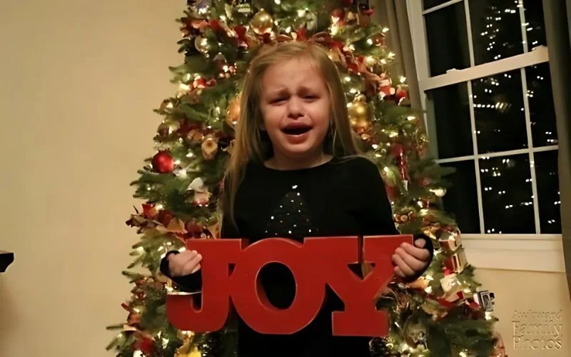 little girl standing in front of xmas tree and crying