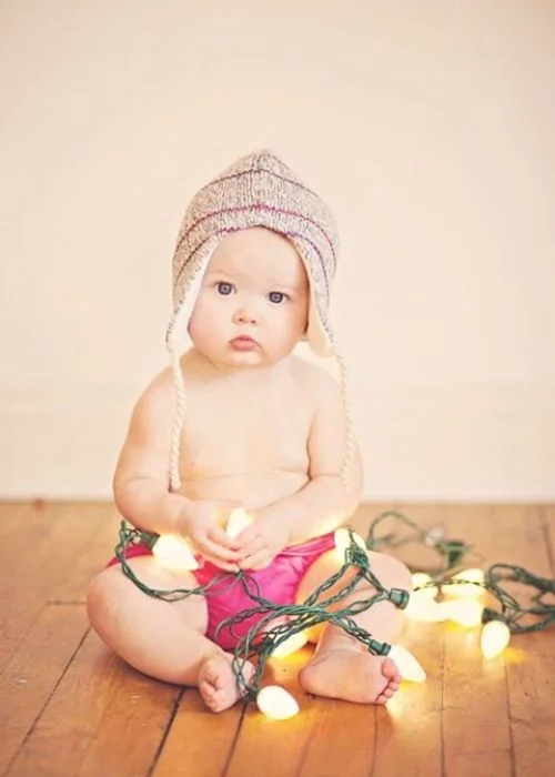 cute little one holding a string of lights, toddler with fairy lights, child playing with string lights