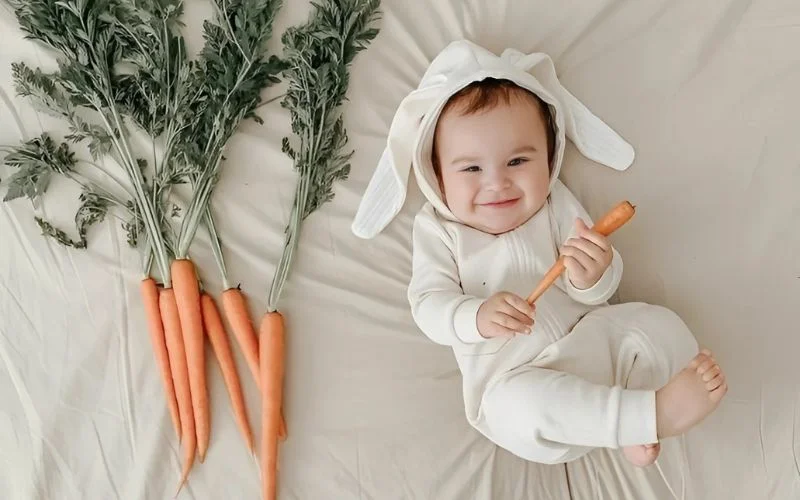 easter infant photo ideas for a baby munching on a carrot, easter-themed baby photos, baby rabbit costume photoshoot